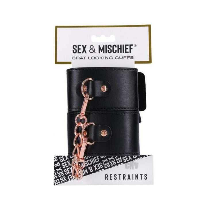 Black vegan leather locking cuffs with rose gold chain and hardware, packaged on a white hang card labeled Sex & Mischief restraints.