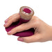 Hand holding a maroon and gold glitter handheld massager with a circular control button on top.