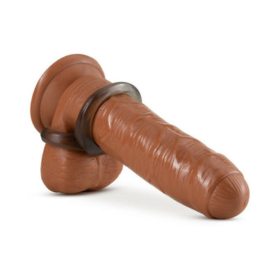 Transparent stretchy cock ring and ball strap displayed on a realistic brown silicone model.