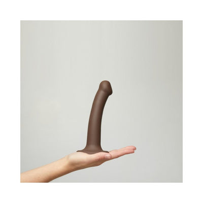 Hand holding a medium-sized, bendable dual-density silicone dildo with a suction base in dark brown color.