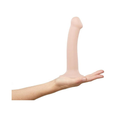 Hand holding a small, bendable, flesh-toned silicone dildo with suction cup base on a white background.