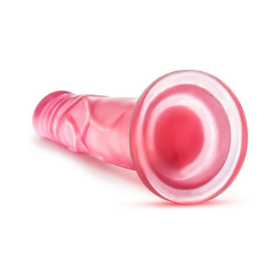 Pink translucent realistic dildo with suction cup base lying on white background.