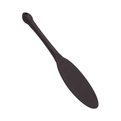 Black silicone paddle with a long handle and tapered, flat striking surface designed for targeted impact play.