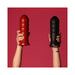 Hands holding two large textured silicone toys in red and black against a red background.