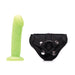 Lime green realistic dildo with detailed texture and black adjustable velvet strap-on harness with metal snaps.