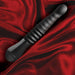 Black Temptasia Lazarus thrusting dildo with ribbed shaft and ergonomic handle on red satin fabric background.