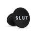 Black silicone butt plug with a round base featuring the word SLUT in bold white letters.