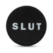 Black silicone butt plug with a round base featuring the word SLUT in bold white letters.