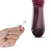 Hand holding magnetic USB charging cable near the base of the Temptasia Trixie thrusting dildo in wine color.