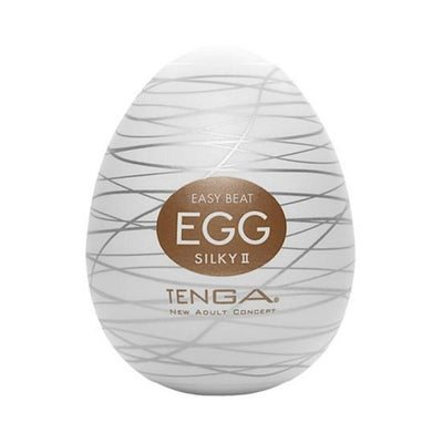 Compact white Tenga Egg Silky 2 with silver swirl design and gold label on front.