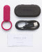 Red silicone vibrating ring with USB charging cable, black storage case, and user manual on white background.