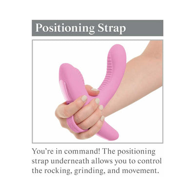 Hand holding pink Threesome Rock N Grind vibrator highlighting the positioning strap for control of movement.