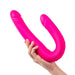 Hand holding a flexible, bright pink silicone double-ended adult toy with two curved shafts.