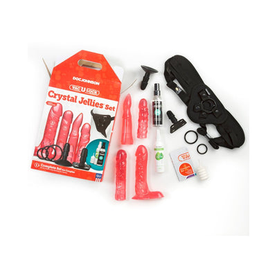 Vac-U-Lock Crystal Jellies Set in pink with four attachments, adjustable harness, lube, cleaner, and accessory rings on white background.