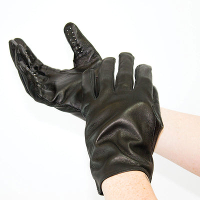 Black leather gloves with small metal tacks on fingertips, worn on hands against a white background.