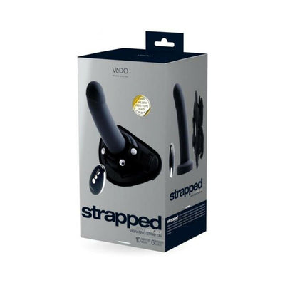 Packaging box of Vedo Strapped rechargeable black strap-on with remote control and adjustable harness shown on front and side.