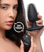 Woman holding a black silicone vibrating butt plug and wireless remote control with voice activation feature.