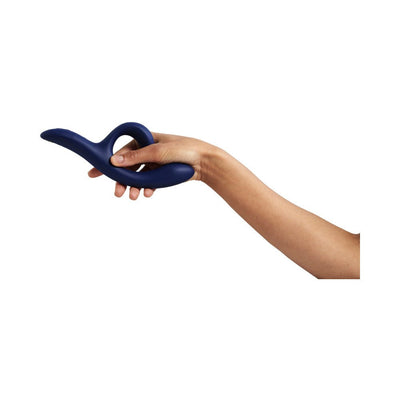 Hand holding a midnight blue We-Vibe Nova 2 flexible dual stimulator against a white background.