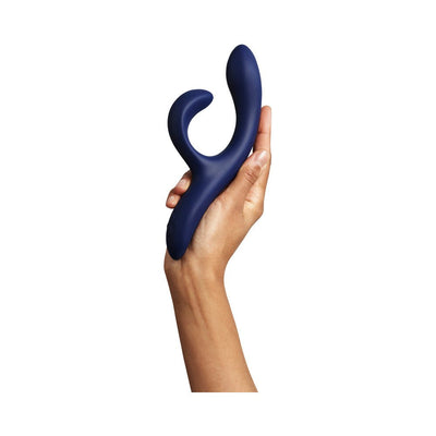 Hand holding a midnight blue We-Vibe Nova 2 flexible dual-stimulation vibrator against a white background.