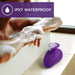 Purple Wellness Palm Sense waterproof massager resting on bathtub edge with water droplets and foam nearby.