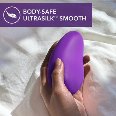 Hand holding a smooth, purple Wellness Palm Sense massager made with body-safe UltraSilk silicone.