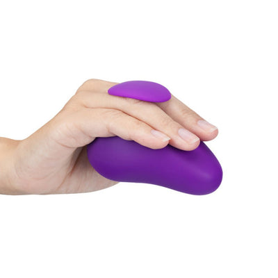 Hand holding a purple Wellness Palm Sense massager with a finger fin for secure grip on a white background.