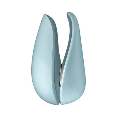 Compact light blue Womanizer Liberty clitoral stimulator with sleek curved design and two interchangeable heads.