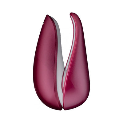 Compact Womanizer Liberty clitoral stimulator in deep red with a sleek, curved design and two flexible arms.