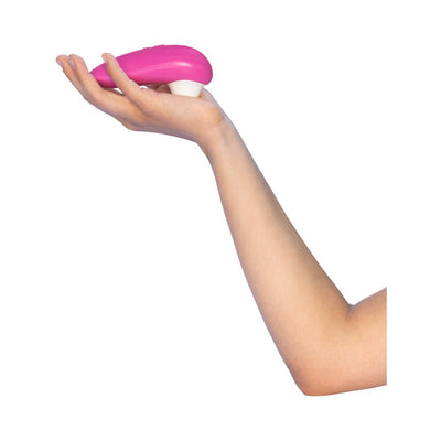 Hand holding a pink Womanizer Starlet 3 clitoral stimulator with white silicone head against a white background.