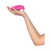 Hand holding a pink Womanizer Starlet 3 clitoral stimulator with white silicone head against a white background.