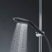 Sleek black Womanizer Wave shower head releasing a fine spray of water, mounted on a chrome shower rail.