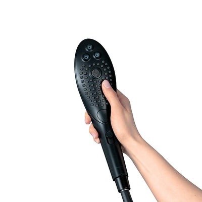 Hand holding the sleek black Womanizer Wave Shower Head Masturbator with textured surface and multiple jet nozzles.