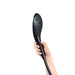 Hand holding the black Womanizer Wave Shower Head Masturbator with textured silicone surface and control buttons.