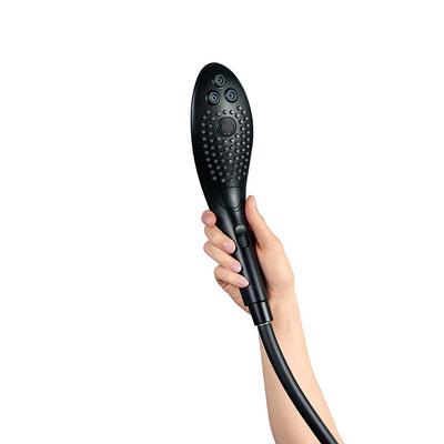 Hand holding a sleek black Womanizer Wave shower head with multiple nozzles and ergonomic design against a white background.
