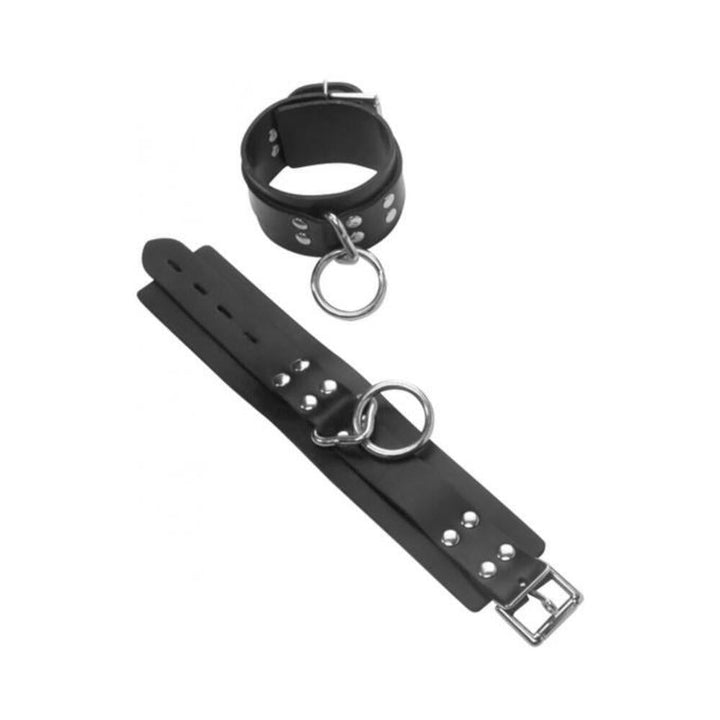 Pair of black leather wrist restraints with silver D-rings and buckle closures, designed for secure and comfortable wear.