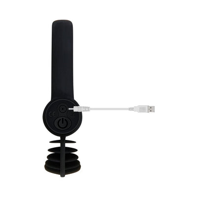 Black dual loop vibrating penis ring with USB charging cable connected, shown from the back on a white background.