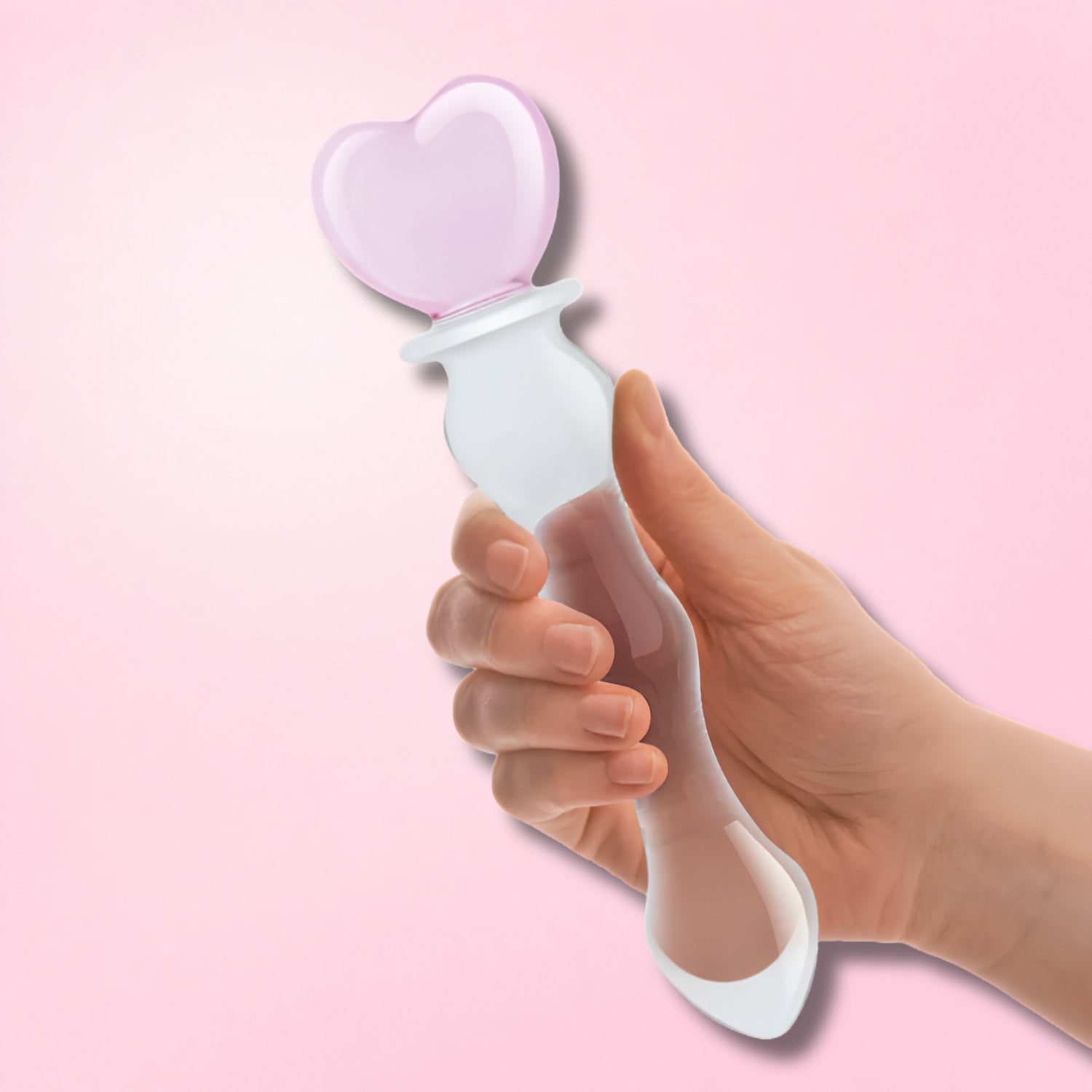 Hand holding a clear, double-ended glass dildo with textured design against a teal background.